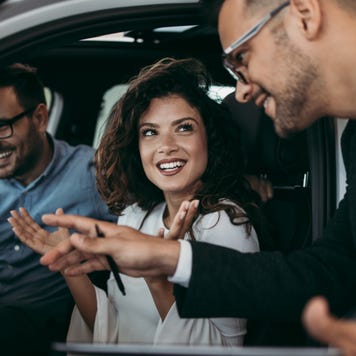 Man and woman sit in a car at a dealership