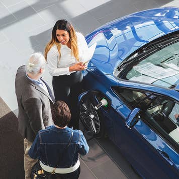 Car dealer talking with customers
