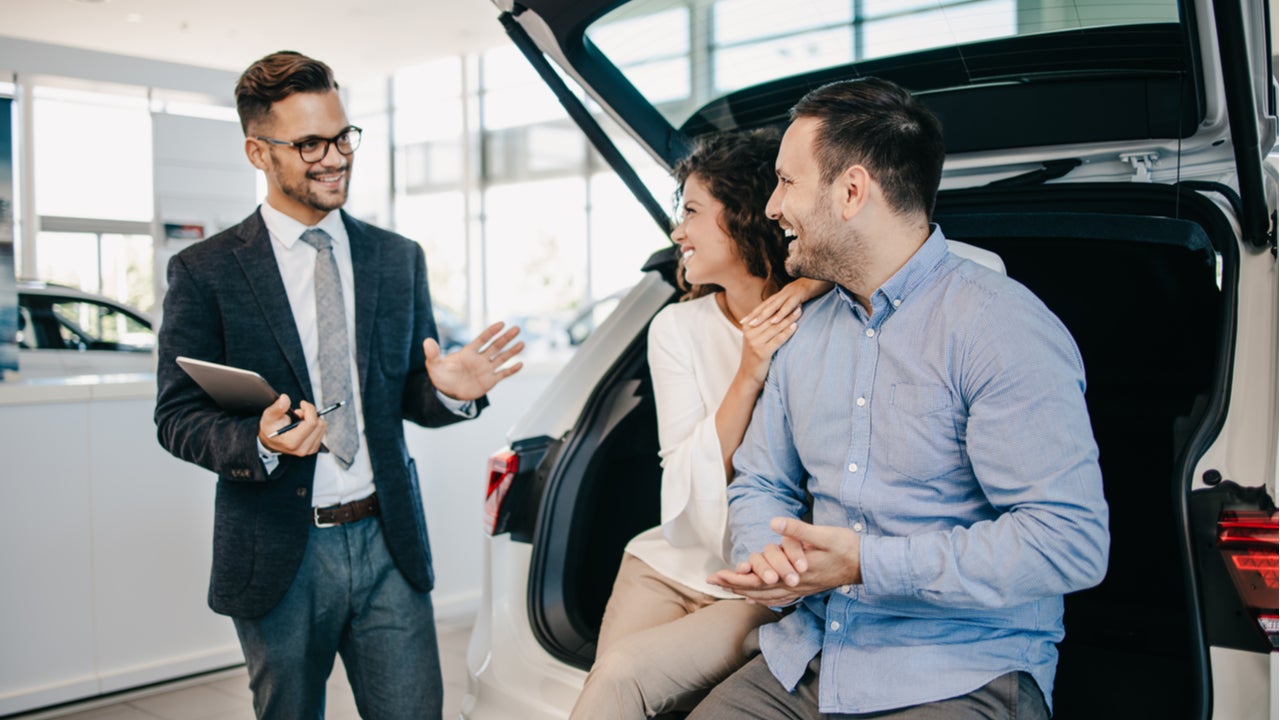Couple listens to sales pitch in car showroom