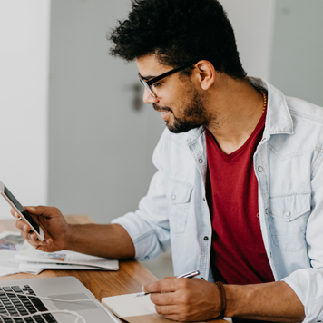 Man sitting at the desk and paying bills with his credit card online using laptop.