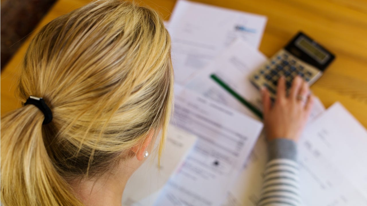 Woman looks through paperwork with a calculator