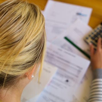 Woman looks through paperwork with a calculator