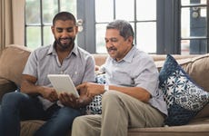 Older man helps young man using tablet