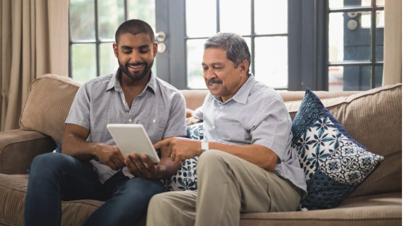 Older man helps young man using tablet