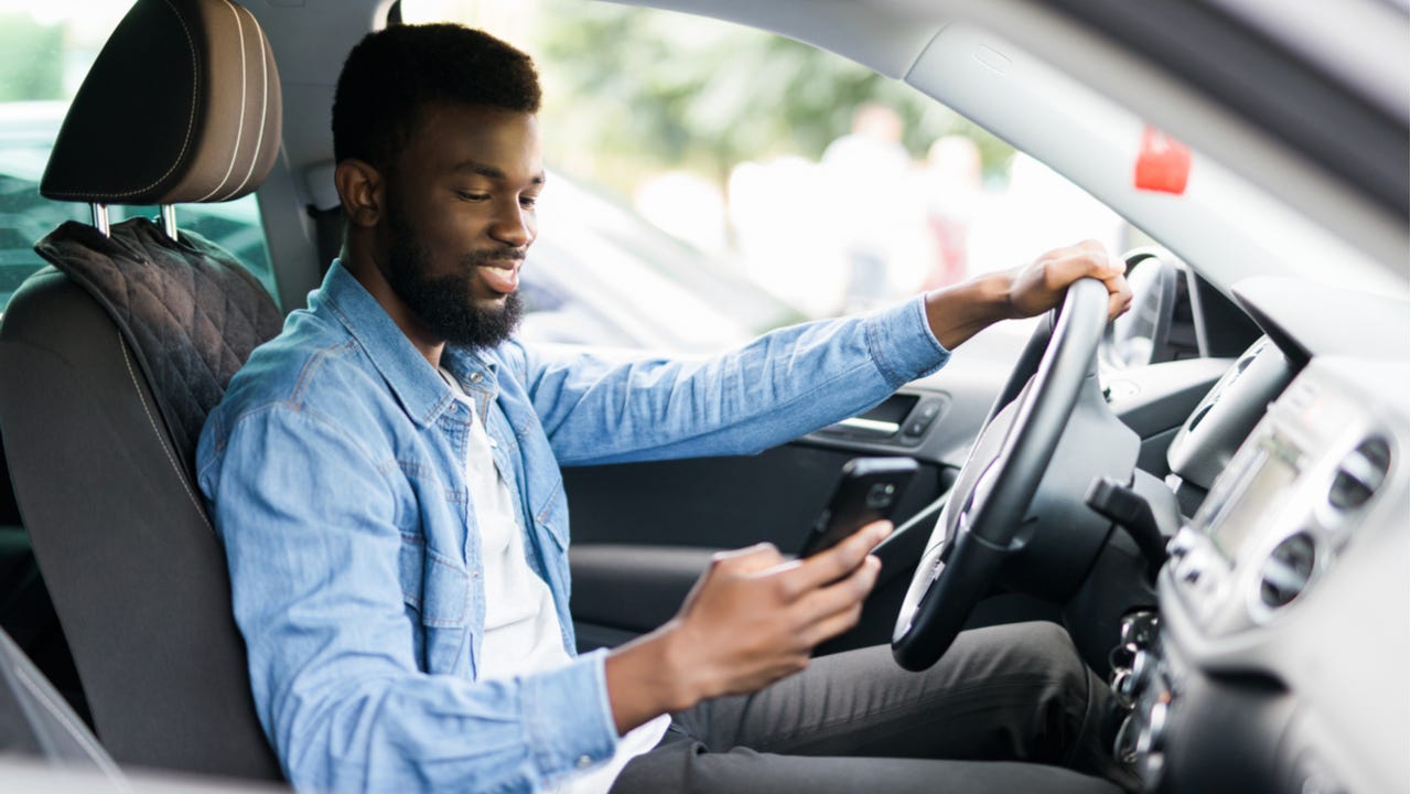 Man checks phone while sitting in car