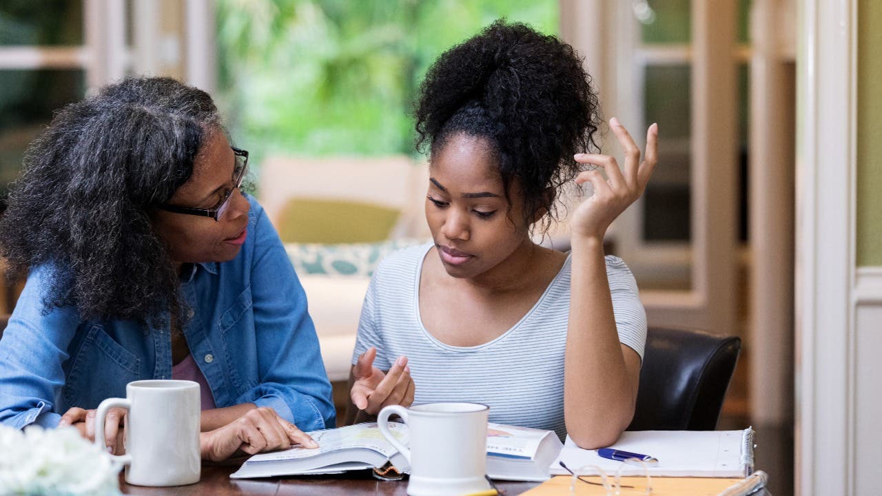 Mother and college student look at textbooks