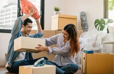 Young Asian couple unpack moving boxes in new apartment