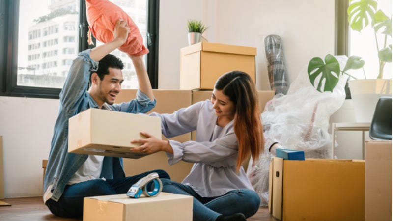 Young Asian couple unpack moving boxes in new apartment