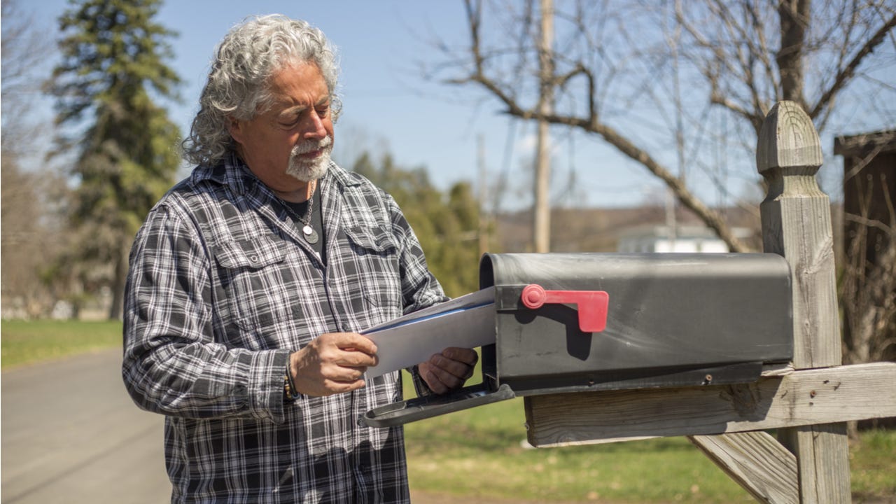 Man looking at mail by the mailbox.