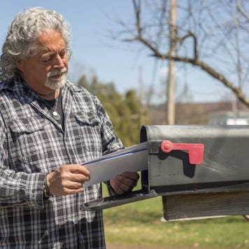 Man looking at mail by the mailbox.