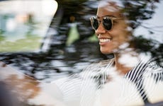 Woman wearing sunglasses while driving and smiling