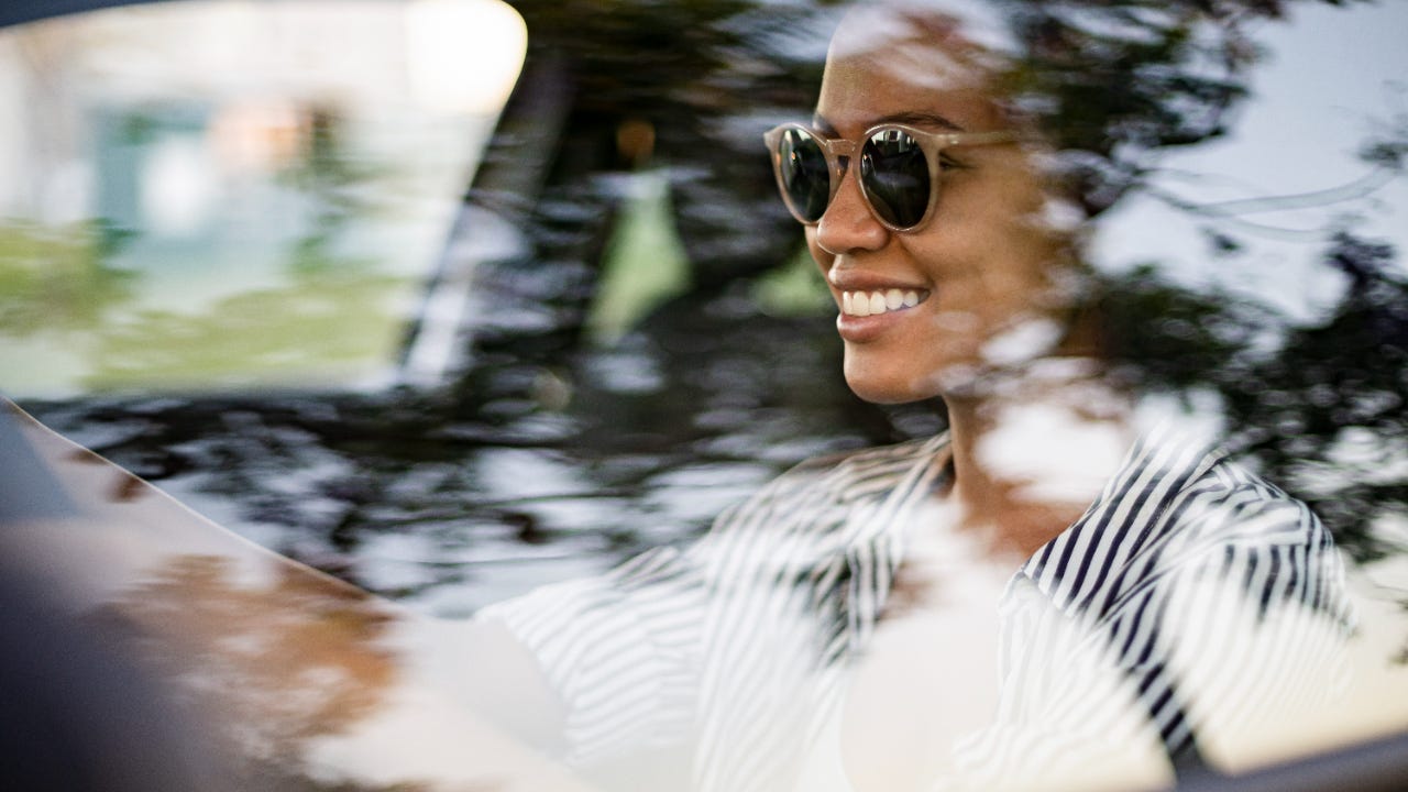 Woman wearing sunglasses while driving and smiling