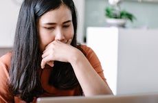 Close up of woman leaning on her hand while looking at laptop