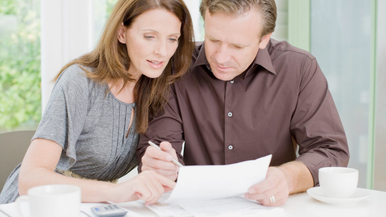 Woman and man leaned close and reviewing a paper at table