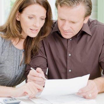Woman and man leaned close and reviewing a paper at table