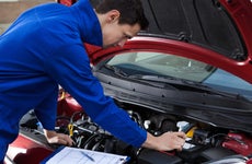 Mechanic looks under the hood of a car