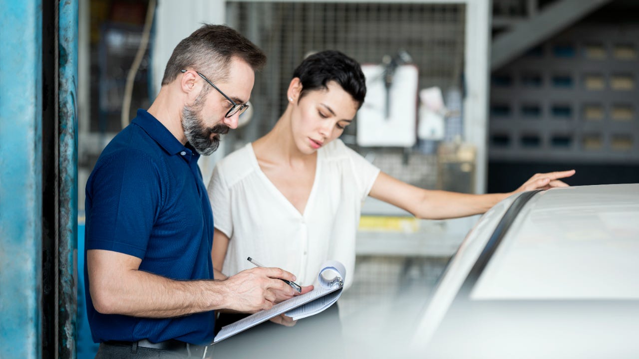 Man and woman looking at clipboard in car repair shop