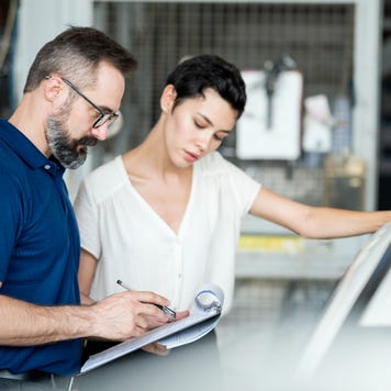 Man and woman looking at clipboard in car repair shop