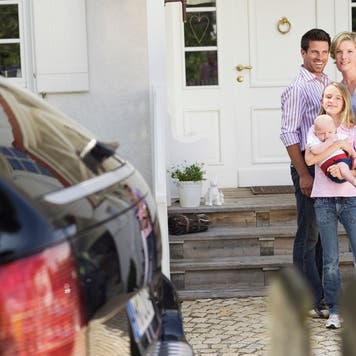 Family with baby standing in front of house