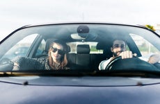 Front view of young woman in sunglasses and man in car