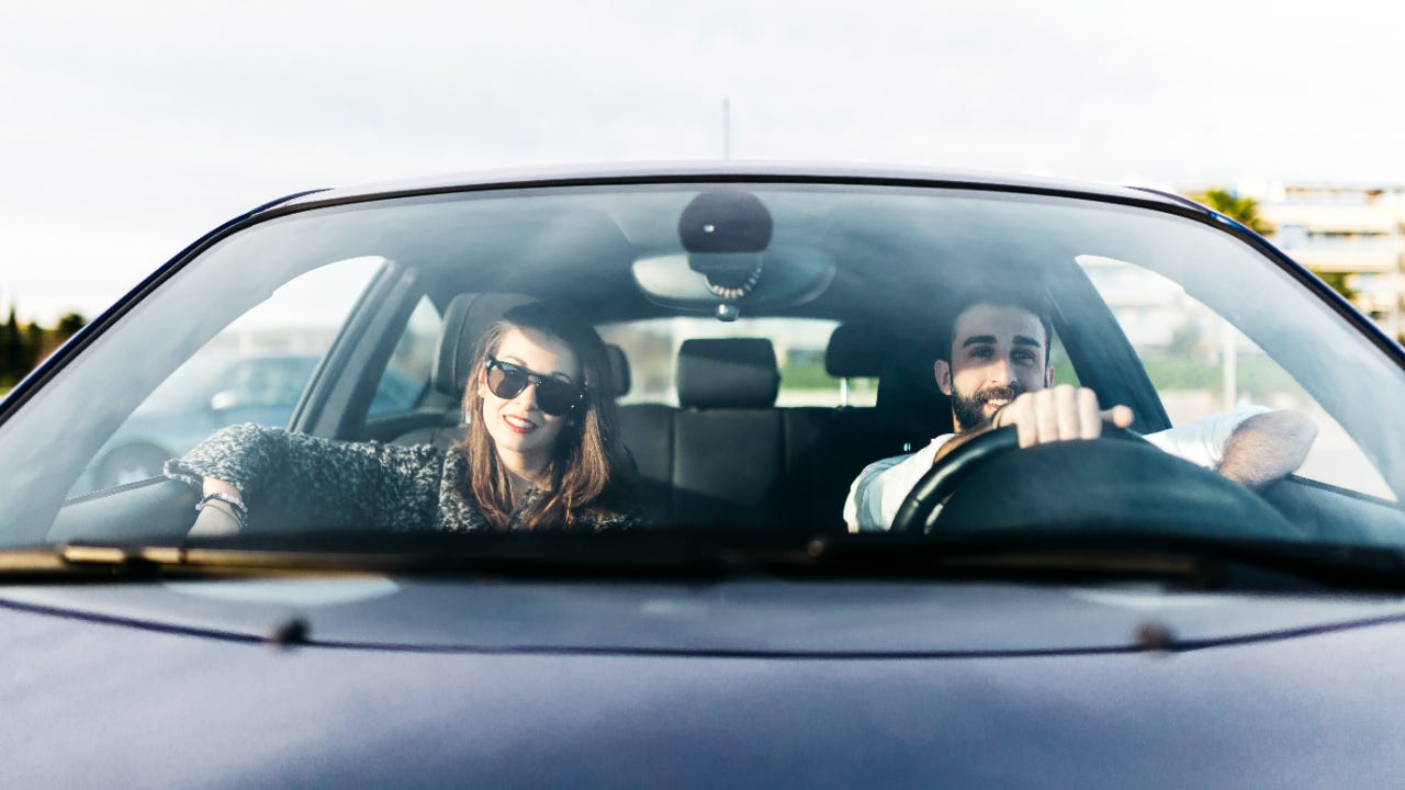 Front view of young woman in sunglasses and man in car