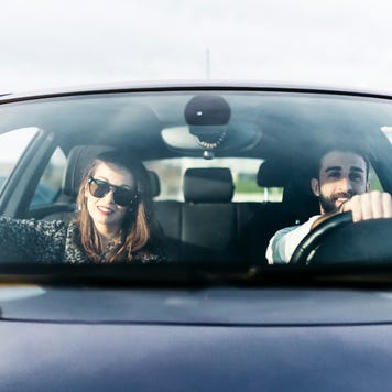 Front view of young woman in sunglasses and man in car