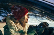 Profile shot of woman in red winter hat and fluffy winter jacket driving