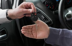 Close up of one person handing another person a car key