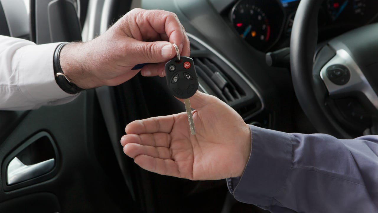 Close up of one person handing another person a car key