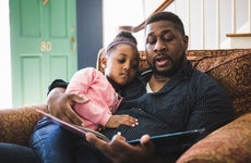 Man reads a book to young daughter