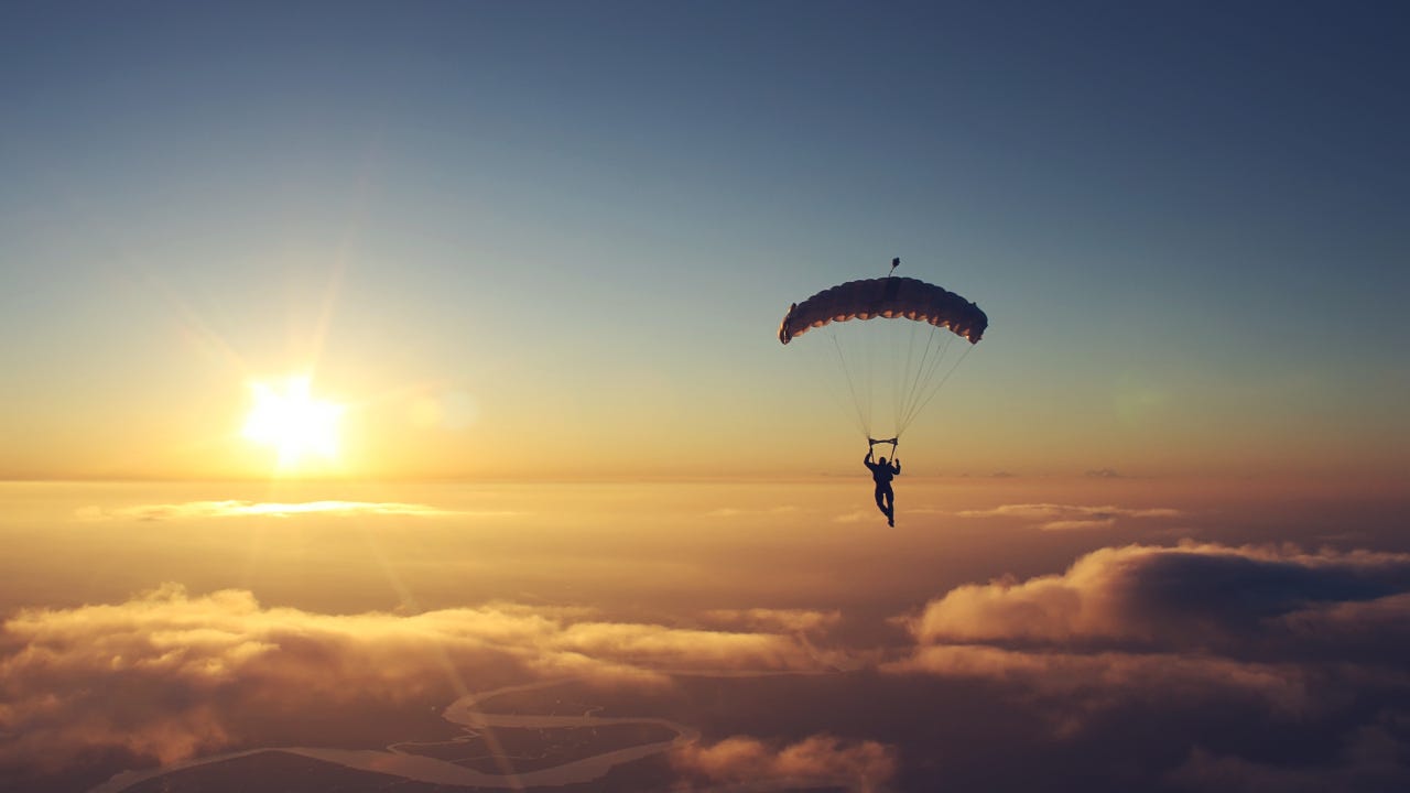 A man parasailing into the sunset.