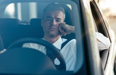Close up front view of businessman in driver's seat with pensive expression