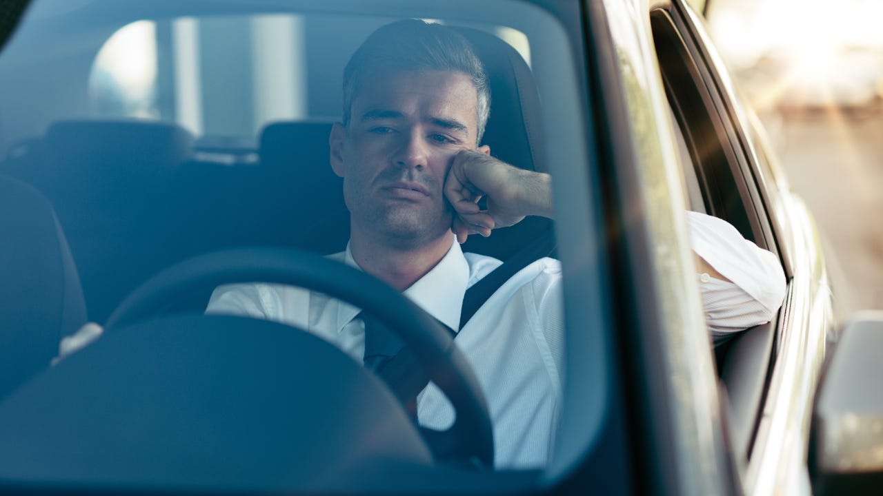 Close up front view of businessman in driver's seat with pensive expression
