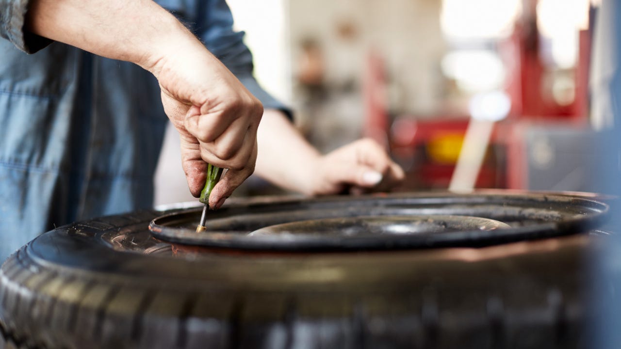 Close up of a mechanic's hands changing a car tire valve in a garage