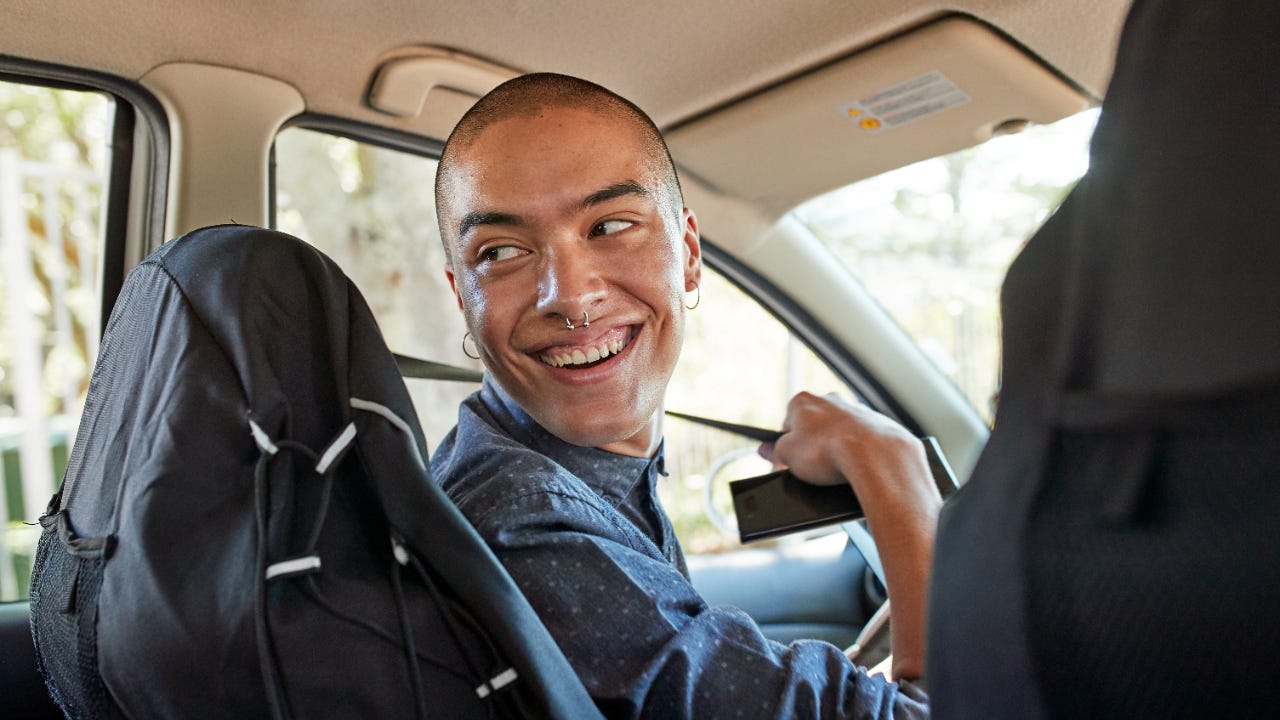 Person in driver's seat of car looking over their shoulder while fastening seatbelt