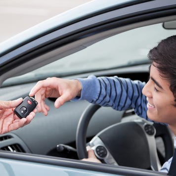 Young man on driver's side of car accepting the key for it through the window