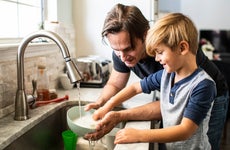 Man washes dishes with son