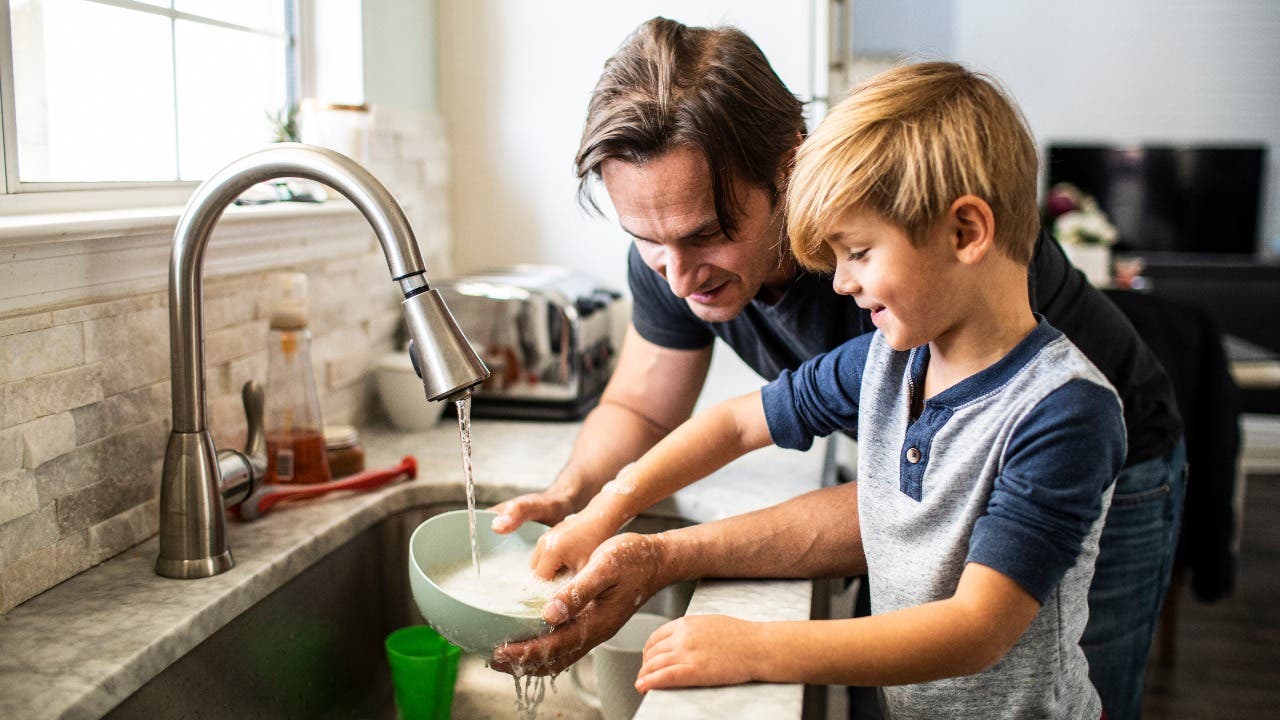 Man washes dishes with son
