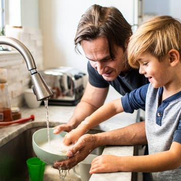 Man washes dishes with son