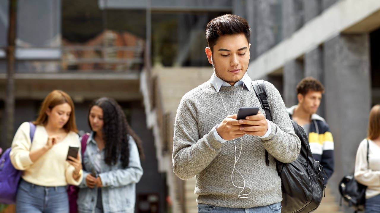 College student looks at phone on campus