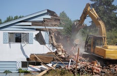 Construction vehicle demolishing a house