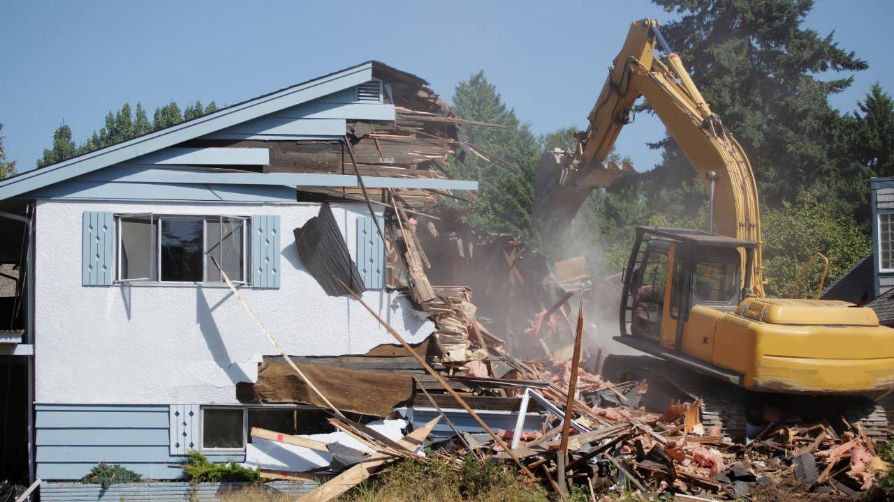 Construction vehicle demolishing a house