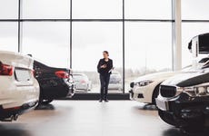Woman standing in car showroom with two cars on either side of her