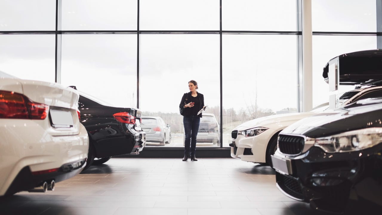 Woman standing in car showroom with two cars on either side of her