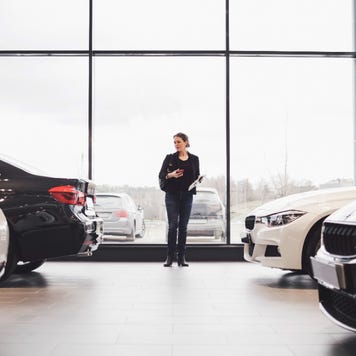 Woman standing in car showroom with two cars on either side of her