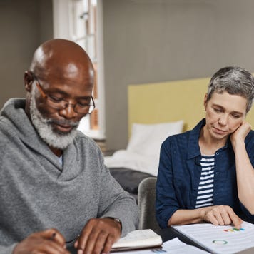 Older interracial couple sitting together at a desk and reviewing their options financially.