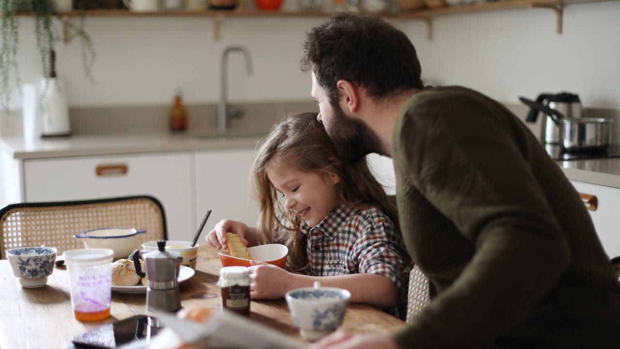 Father and daughter have breakfast in a kitchen