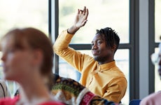 Student raises his hand in college classroom