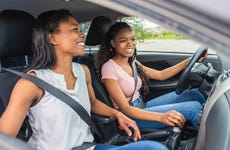Daughter and mother in car, daughter driving, both smiling