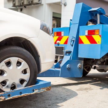White car being towed away by blue tow truck